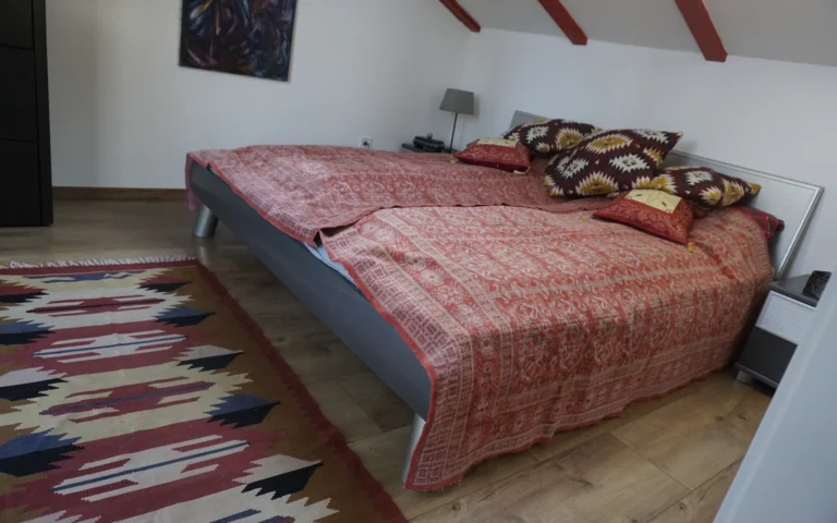 Hálószoba franciaággyal és színes textilekkel a ZegZug vendégházban