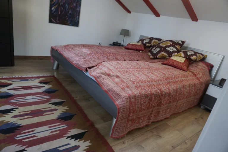 Hálószoba franciaággyal és színes textilekkel a ZegZug vendégházban