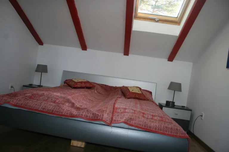 Tetőtéri hálószoba tetőablakkal és látszó gerendákkal a vendégházban