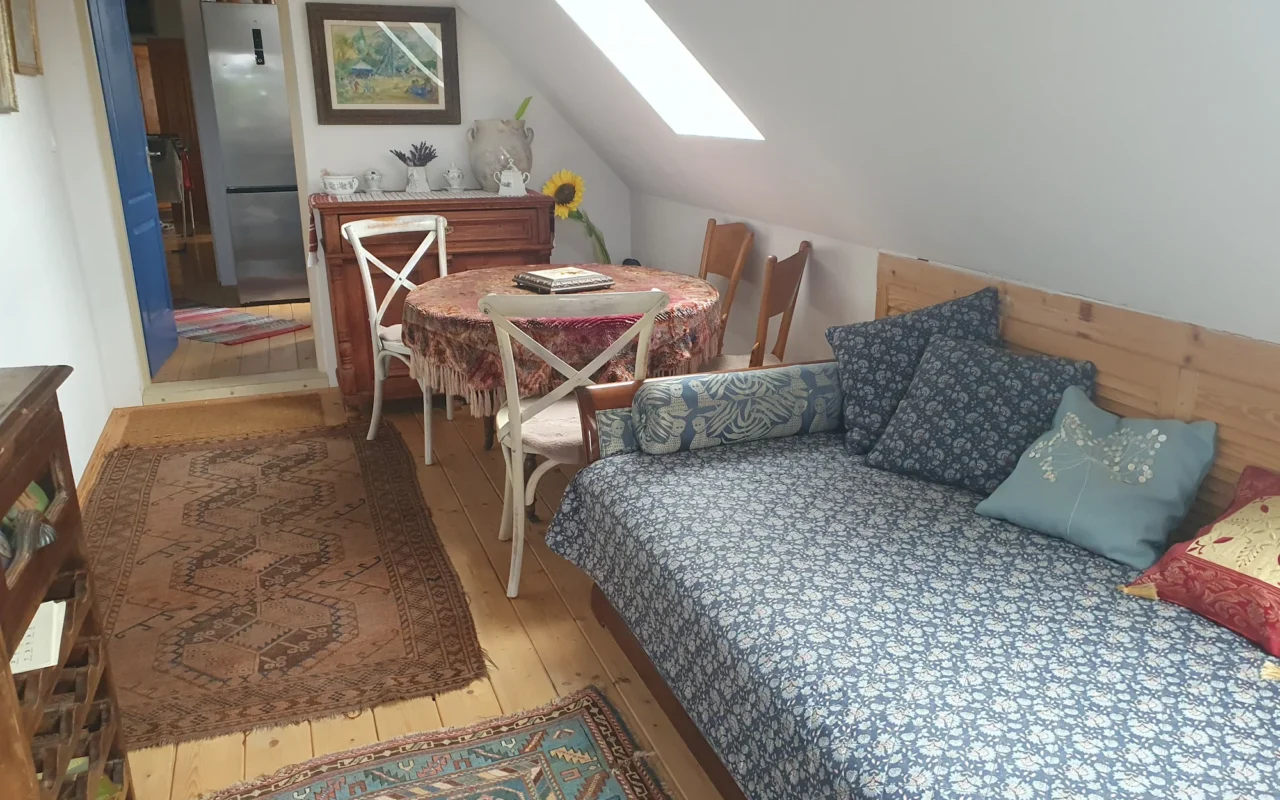 Tetőtéri nappali rész kanapéval és asztallal a vendégházban