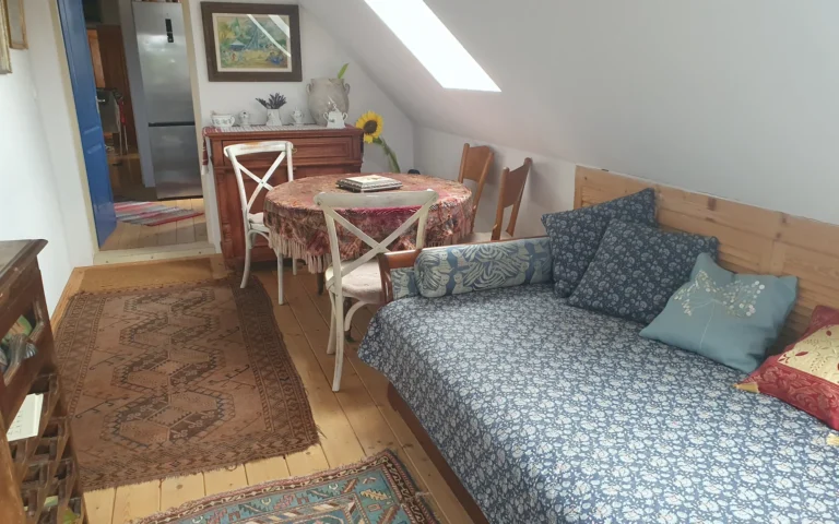 Tetőtéri nappali rész kanapéval és asztallal a vendégházban