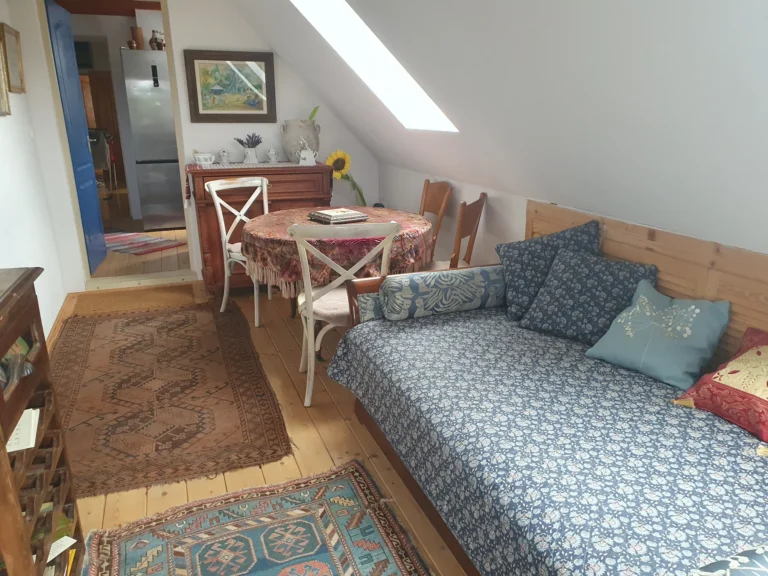 Tetőtéri nappali rész kanapéval és asztallal a vendégházban